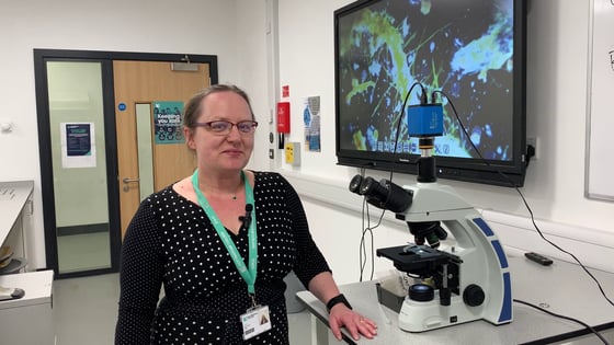 A science lecturer with a microscope in a science lab at the City Hub.