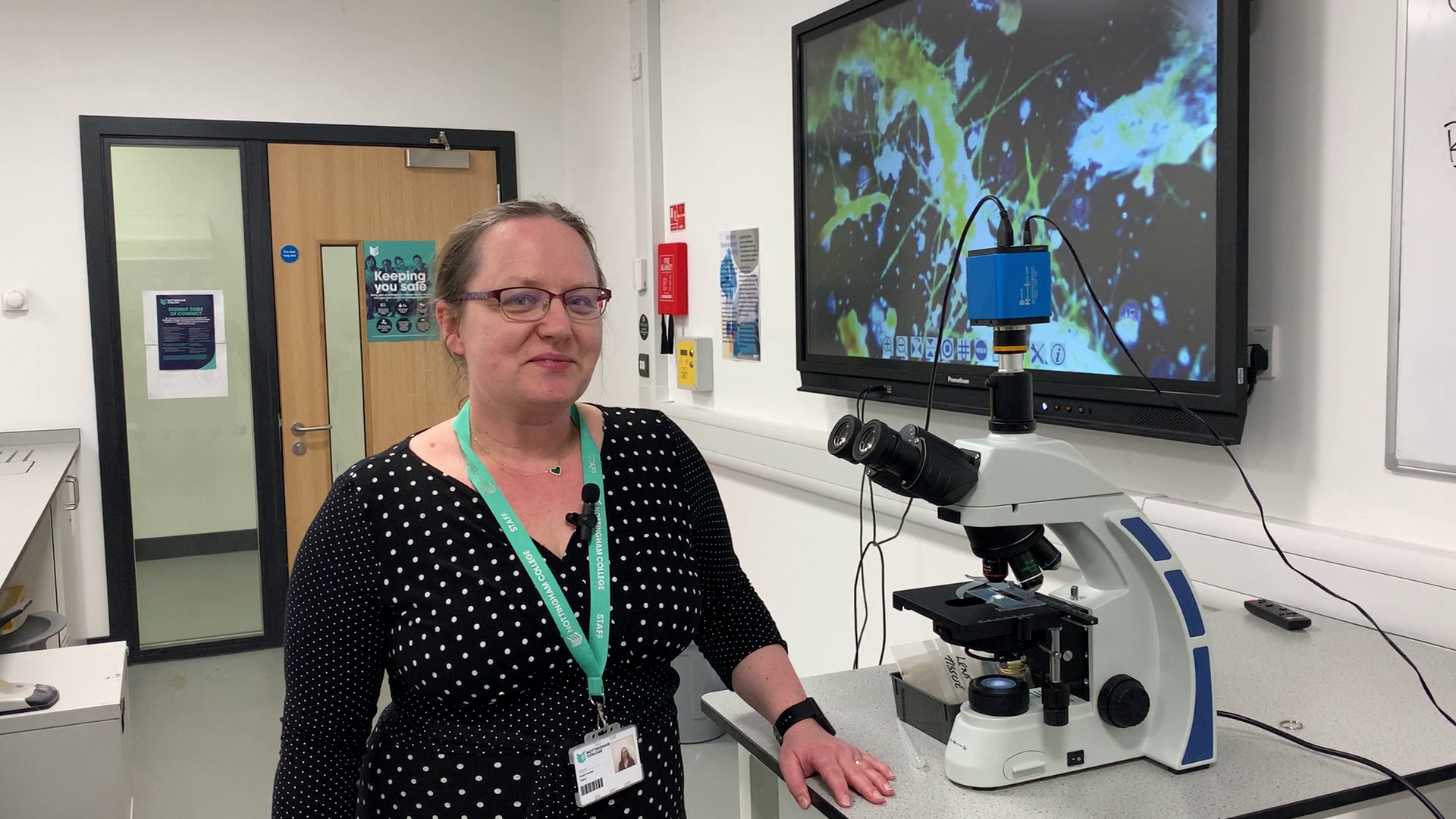 A science lecturer with a microscope in a science lab at the City Hub.