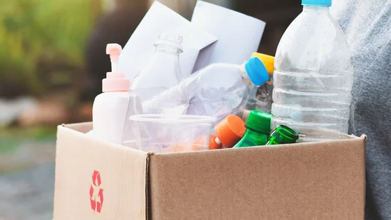 A picture of a student carrying a cardboard box containing recycling.
