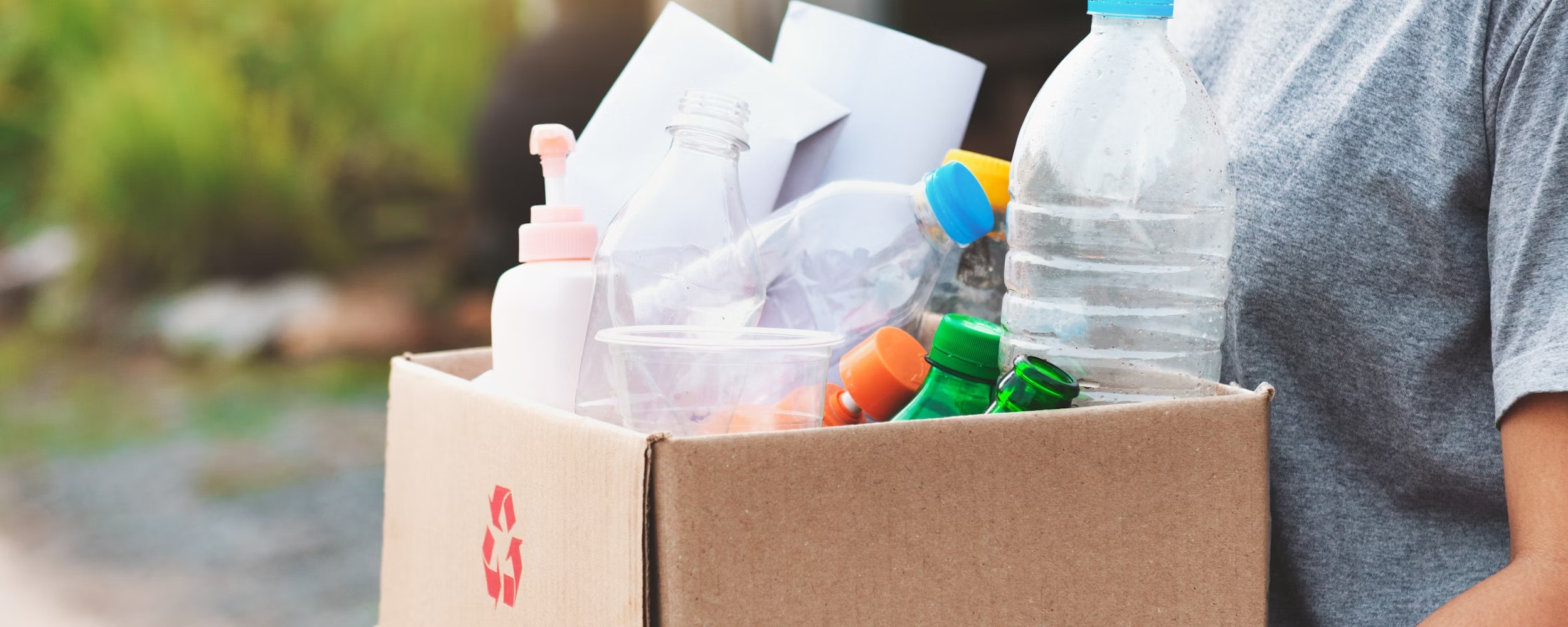 A picture of a student carrying a cardboard box containing recycling.