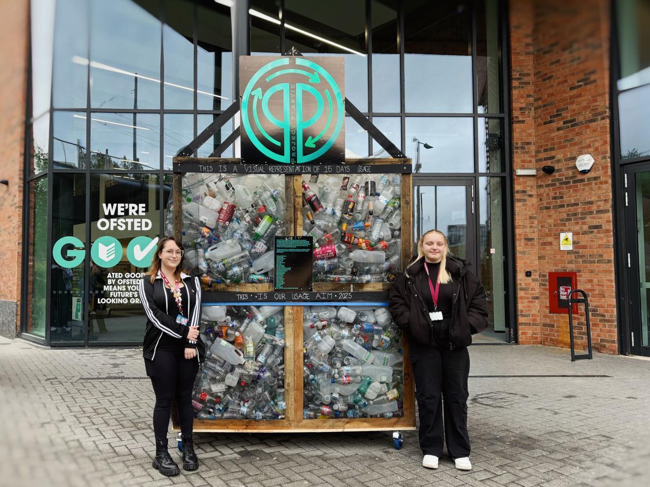 Two students stood in front of their sustainability project