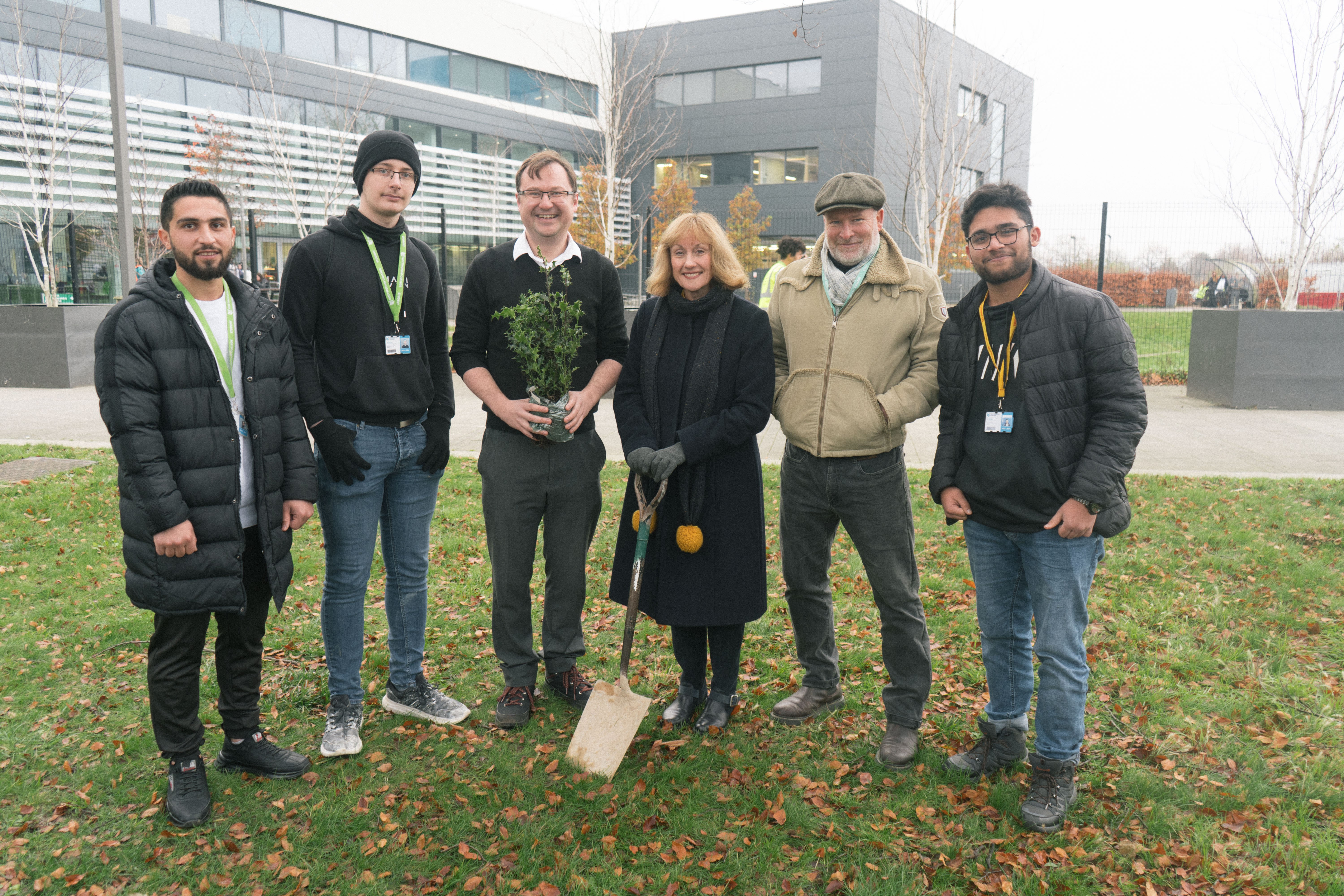 Janet Smith holding a spade at the Basford campus with members of staff and students