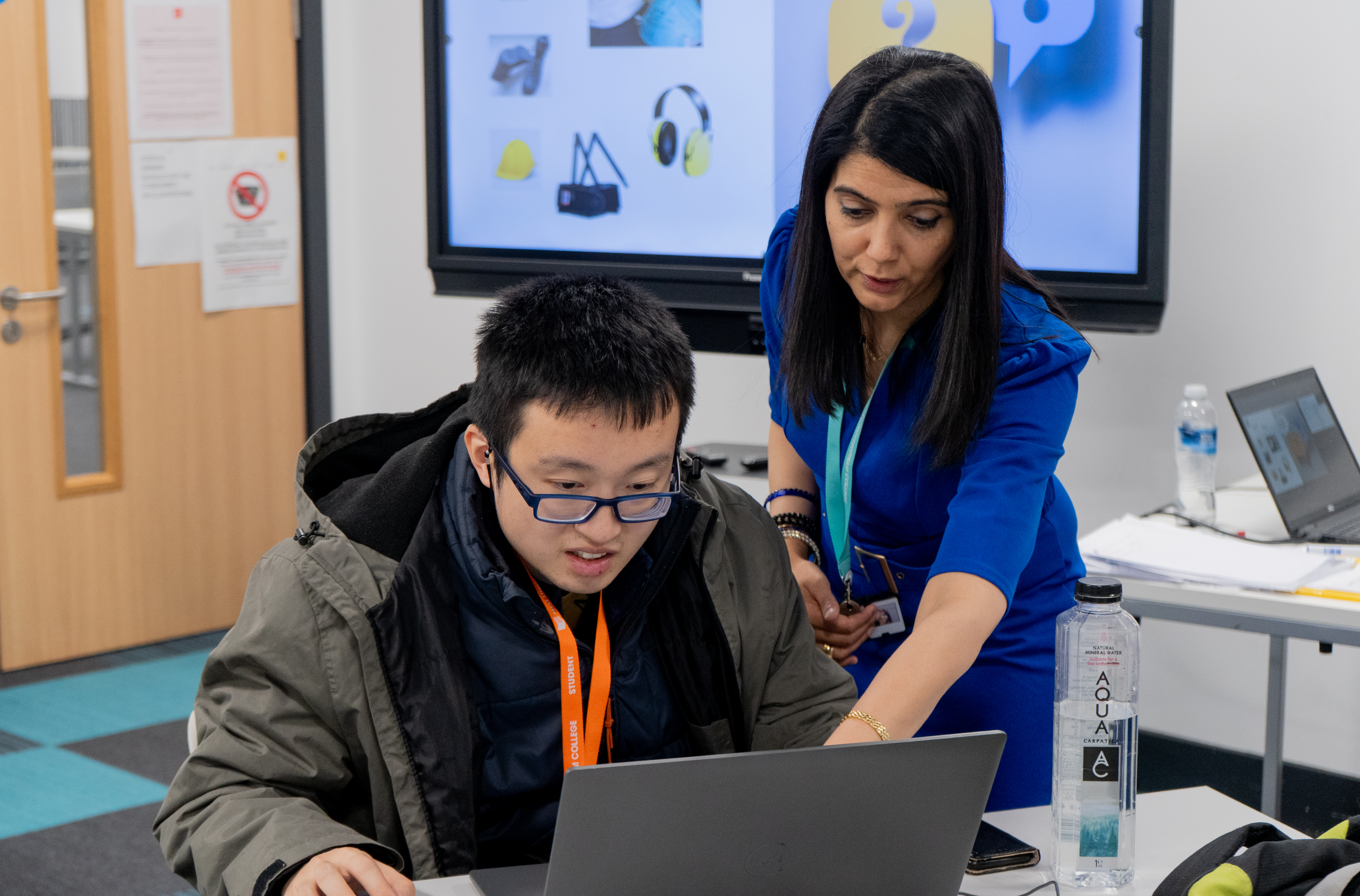 Tutor showing a student how to do something on a laptop