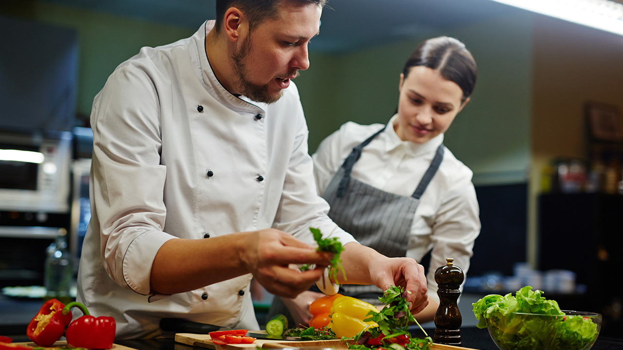 A Chef Apprentice observing a chef preparing food