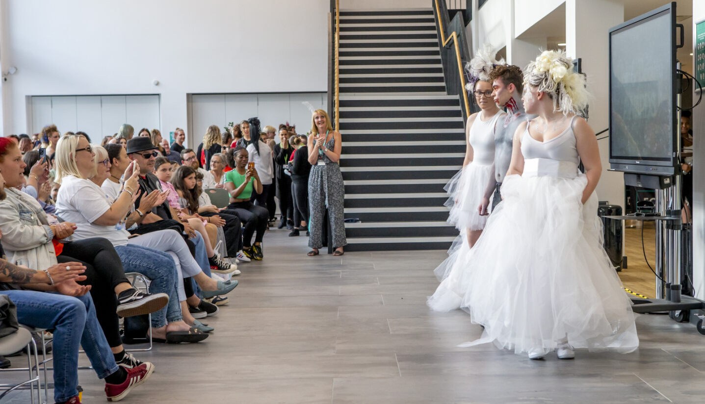 Students wearing their creations at the City Hub with an audience.