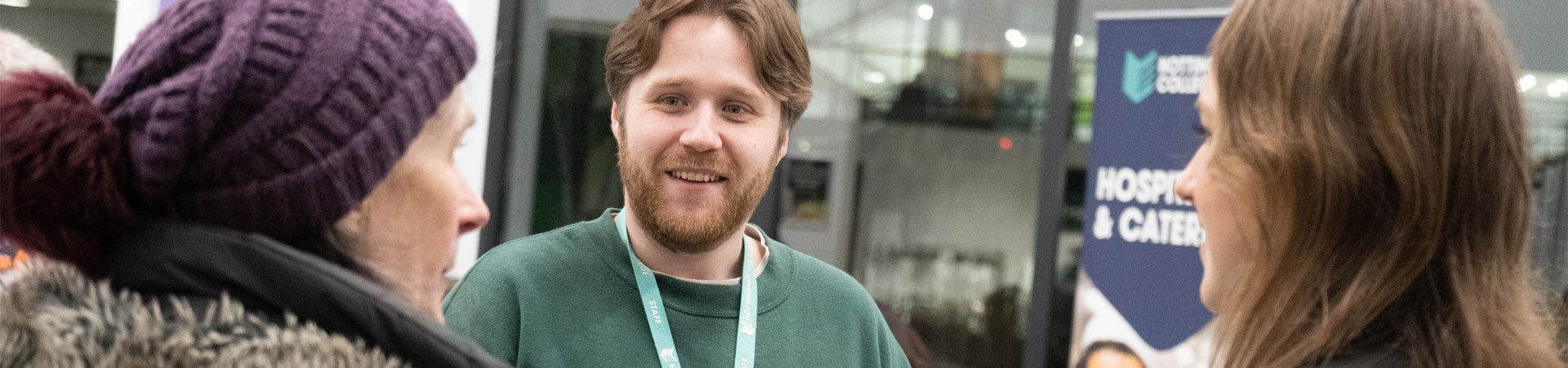 A member of staff taking to two mature students.