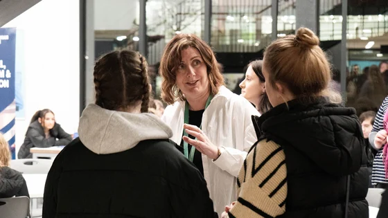 A member of staff explaining something to students an an Open Evening