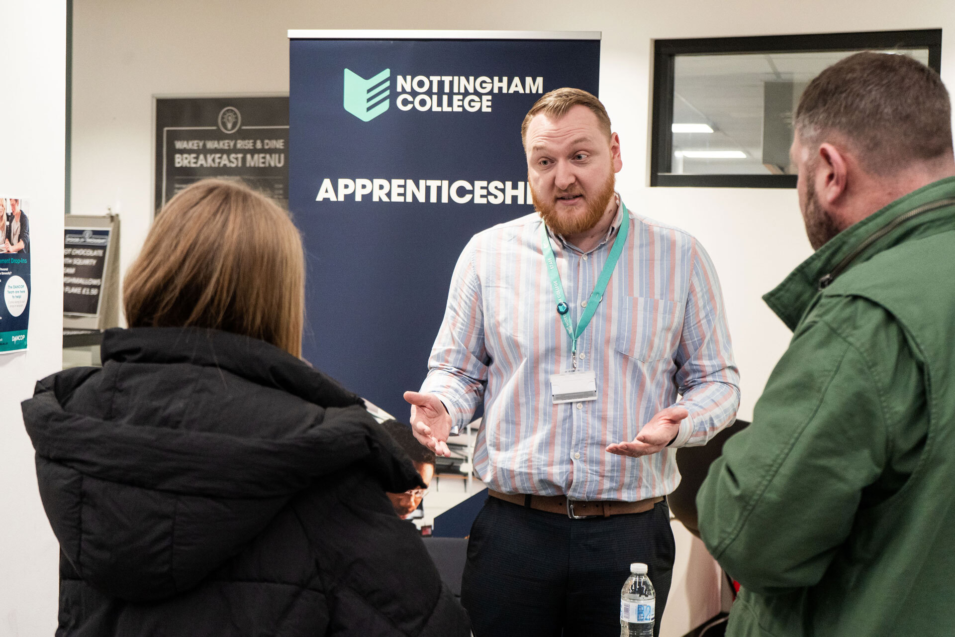 A lecturer talking to visitors at an open evening at the City Hub.