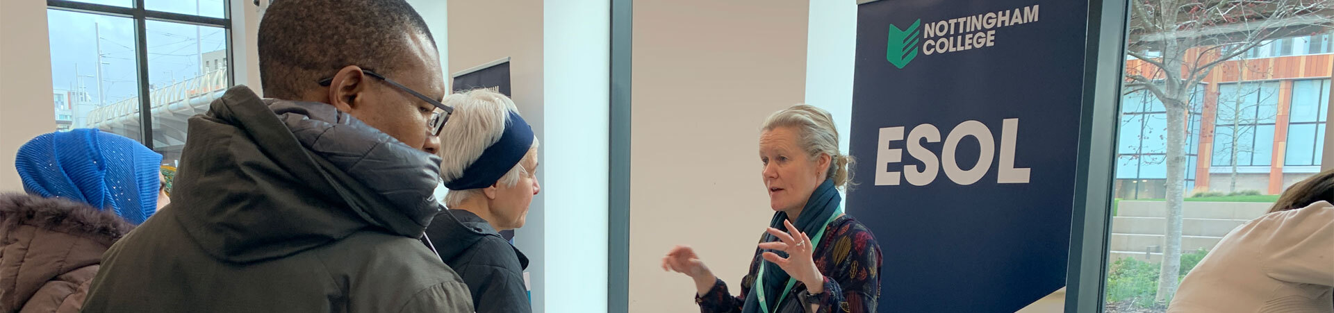 Adult students talking to a staff member about course information.