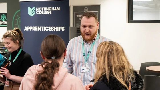 Two people talking to a member of the apprenticeship team at an event