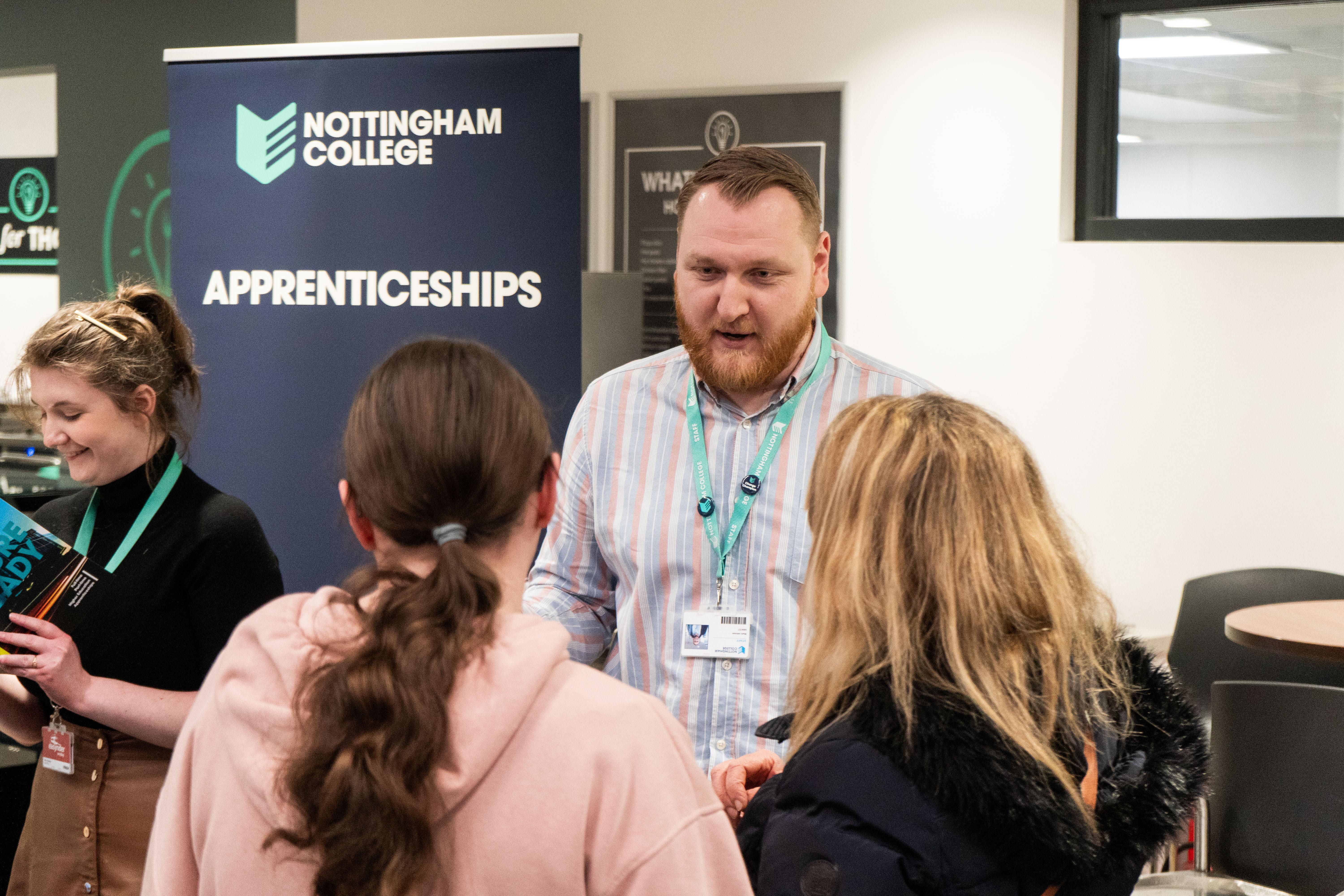 Two people talking to a member of the apprenticeship team at an event
