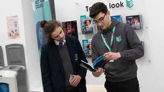 A member of staff talking to a prospective student at an open evening at the City Hub.