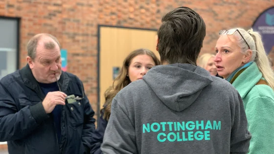 A member of staff talking to visitors at an open evening at the City Hub.