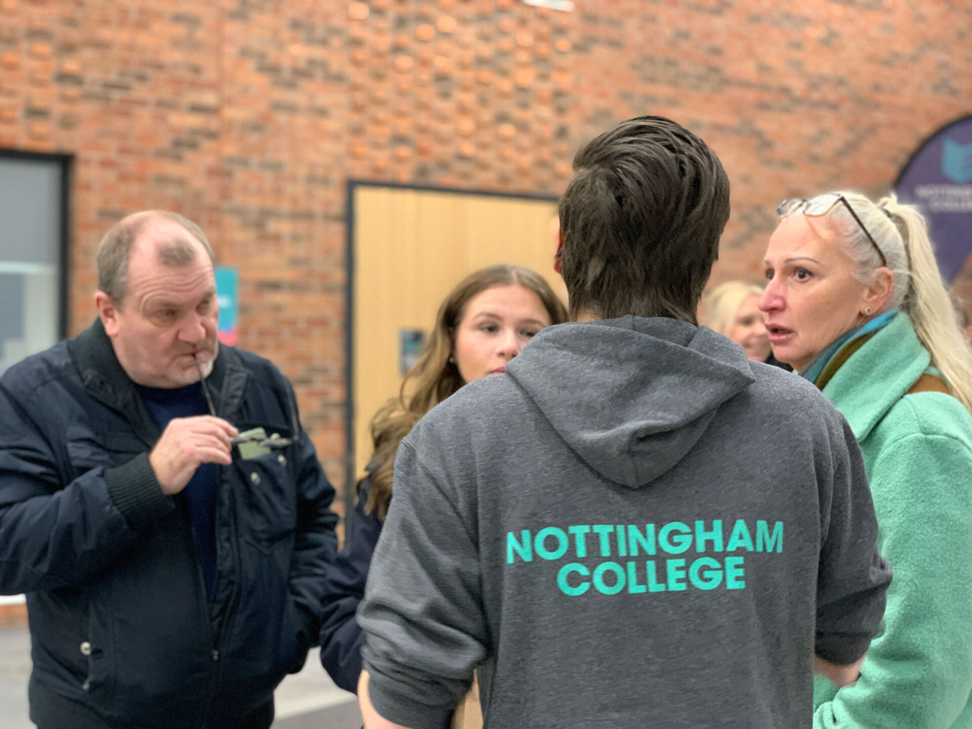 A member of staff talking to visitors at an open evening at the City Hub.