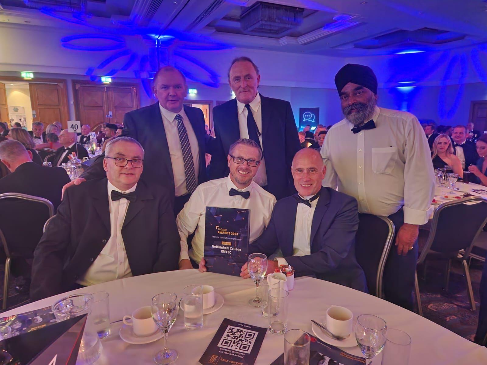 Staff members sat around a table smiling with an award at an awards ceremony