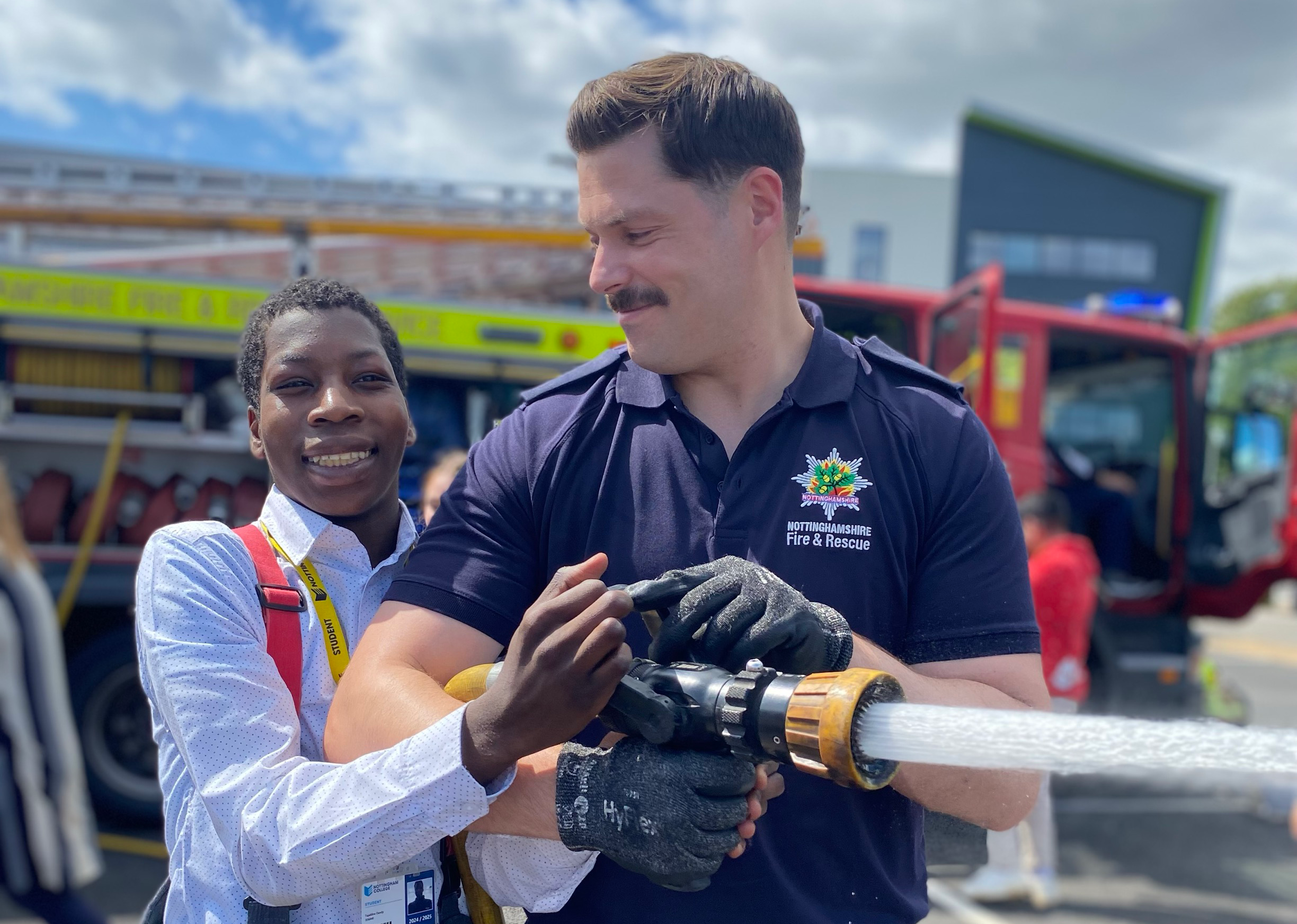 Student using a hose with a fireman