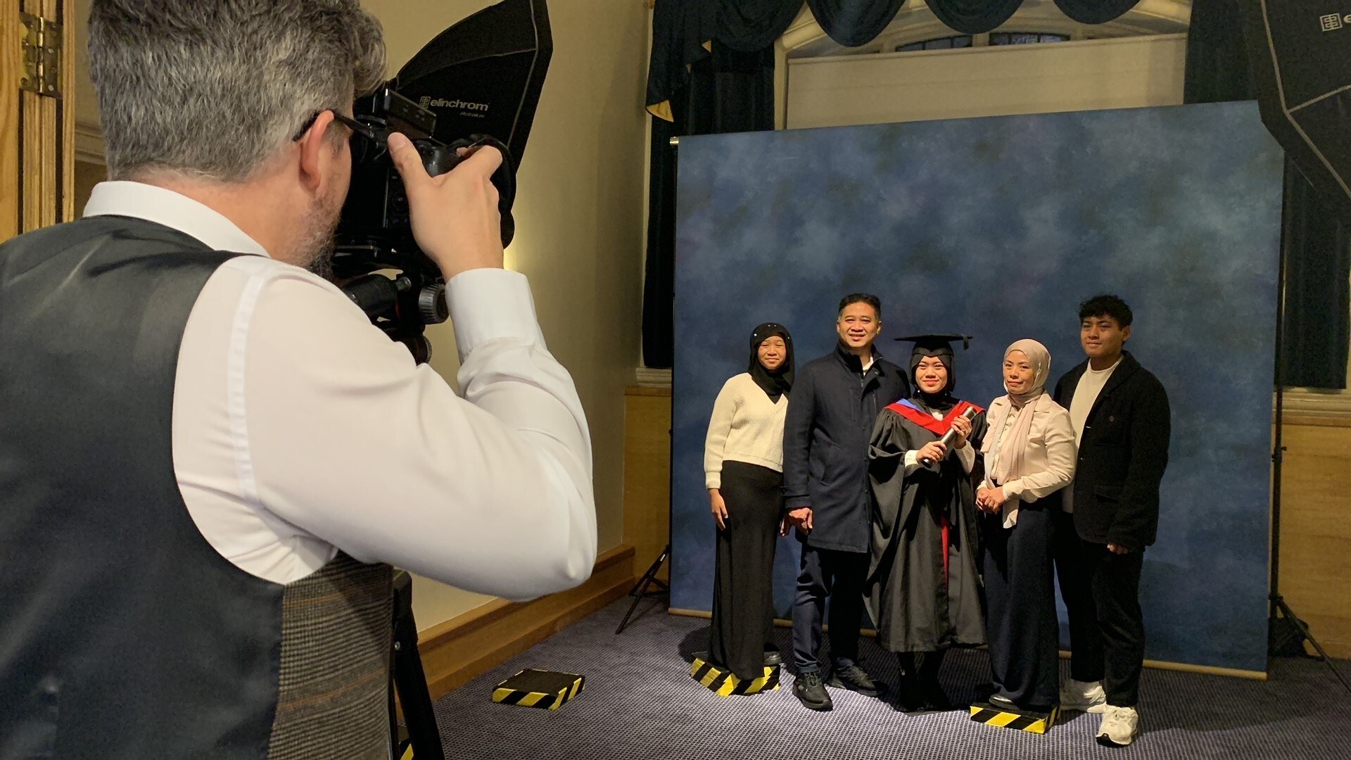 A photographer taking a picture of a graduate with her family