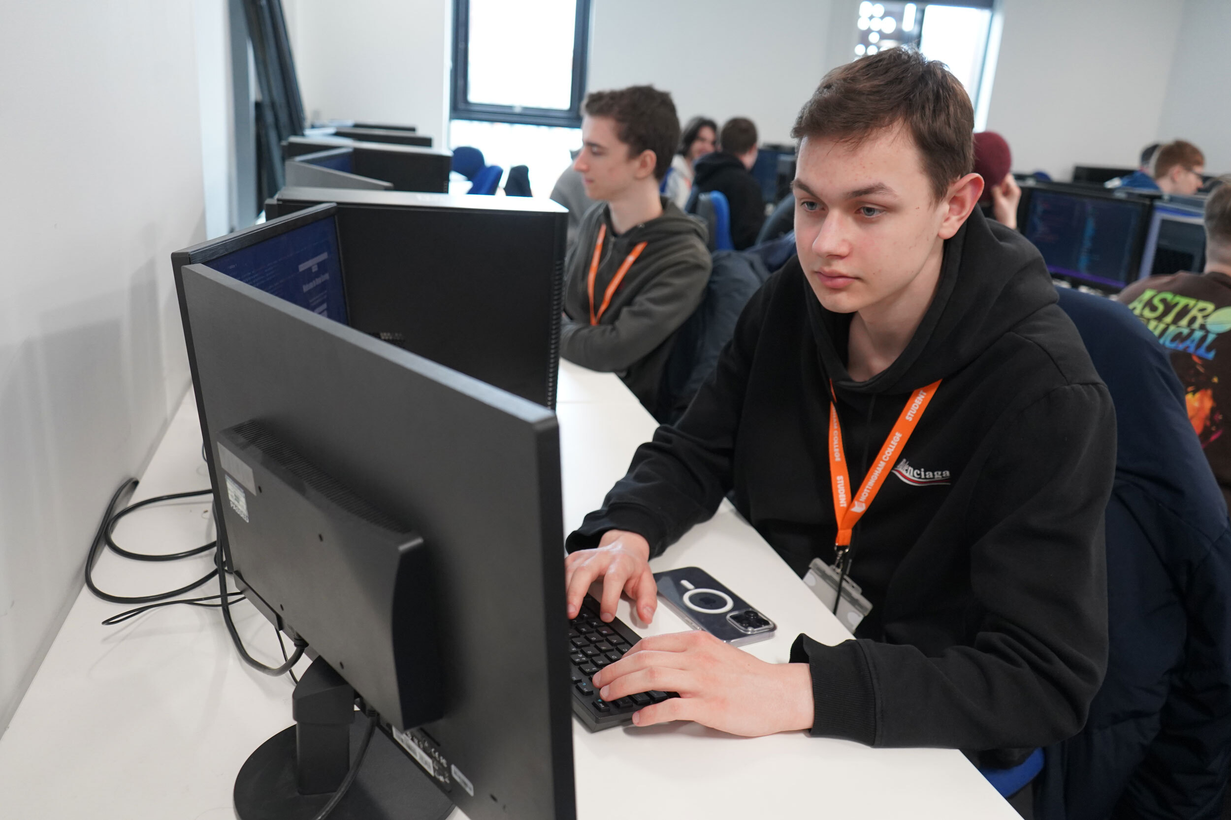 Computing students sat working on a row of computers