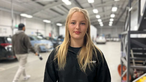 A motor vehicle student stood smiling in a workshop