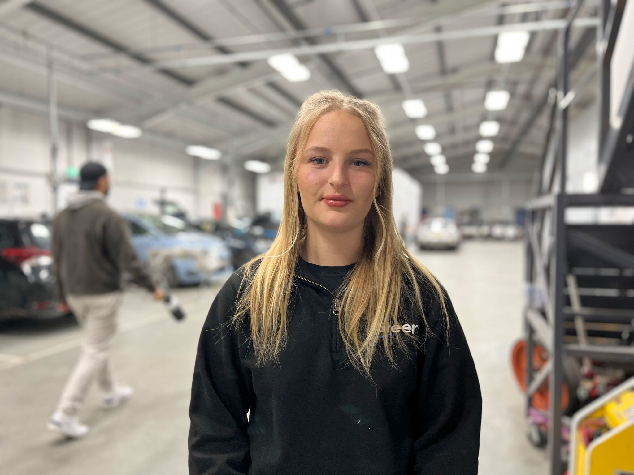 A motor vehicle student stood smiling in a workshop