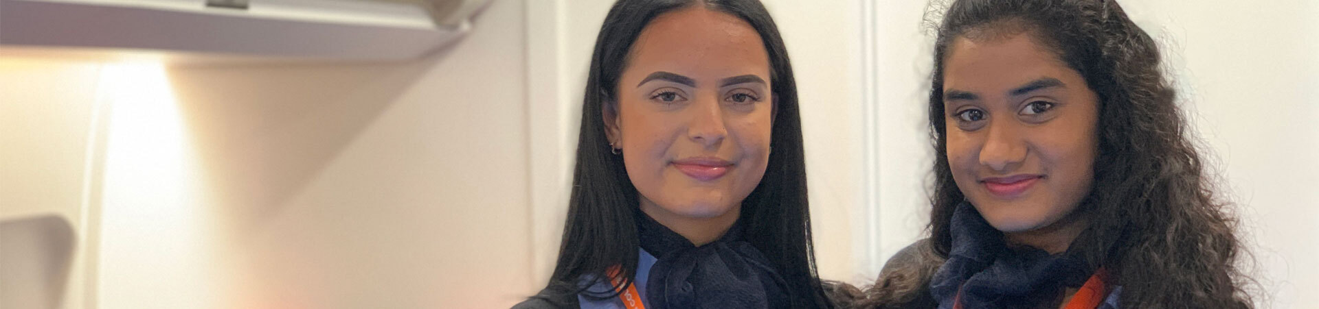 Two students in travel and tourism uniform in the aircraft cabin at the City Hub