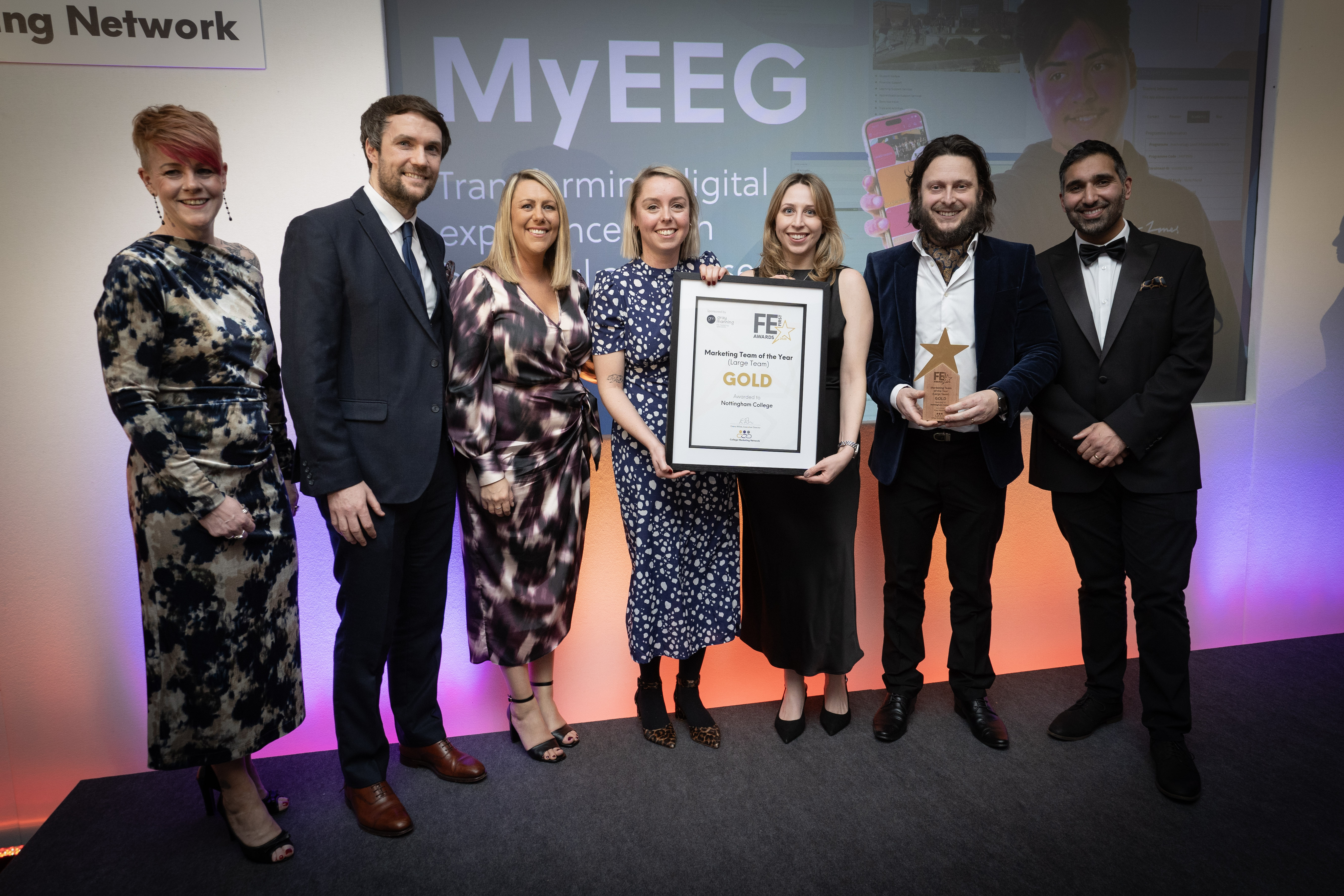 Marketing team members smiling with their award and hosts.