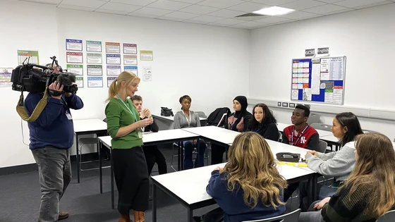 Students and staff in a classroom with a cameraman.