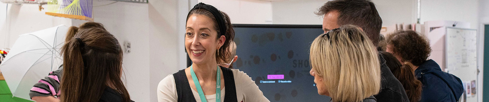 A member of staff talking to students at an open evening