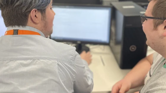 A student and lecturer in front of a computer screen.