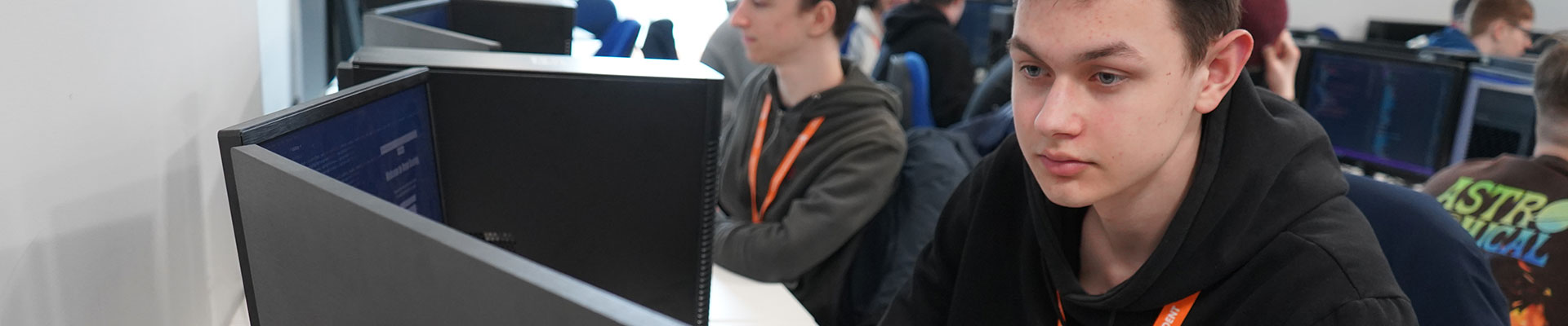 A computing student sitting at a computer in a classroom in the City Hub.