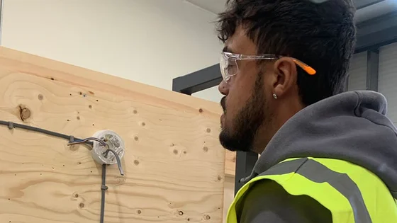 A student looking at a wiring look on a piece of wood.