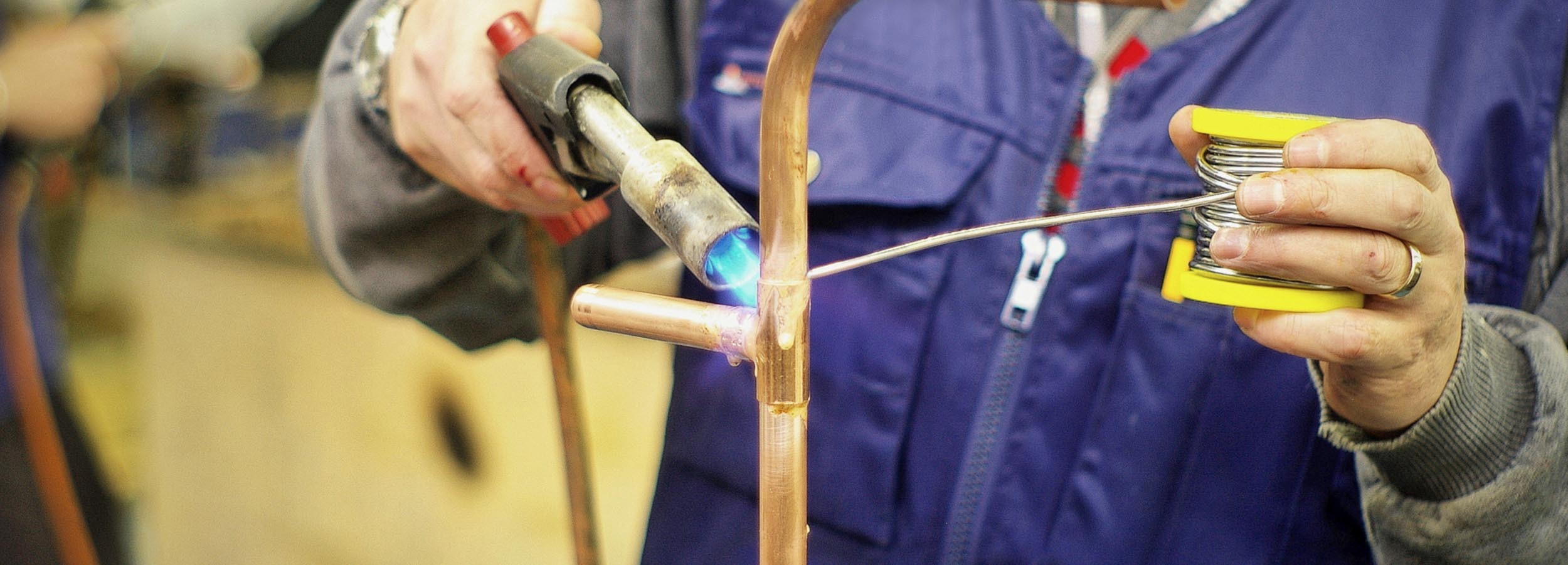 A Engineering student soldering a piece of metal pipe