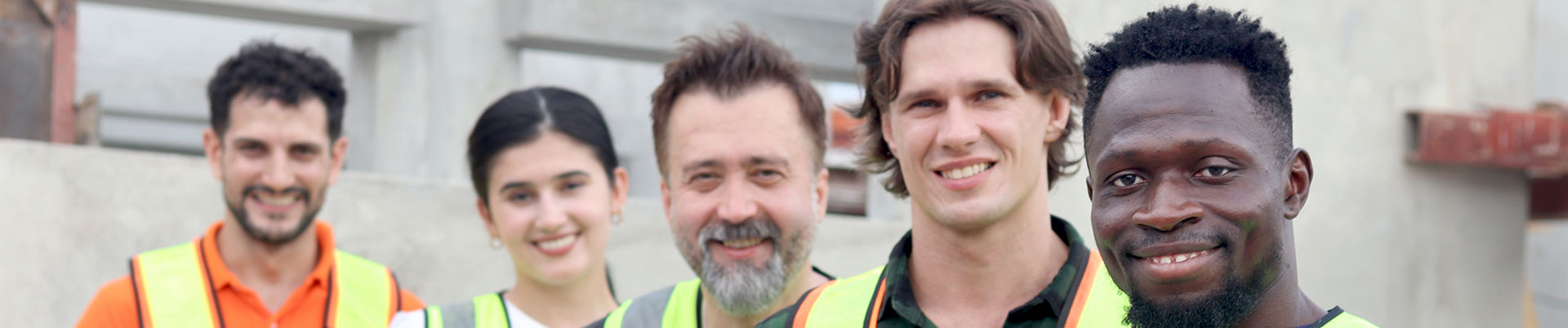 A group of construction workers holding their hard hats and smiling at the camera