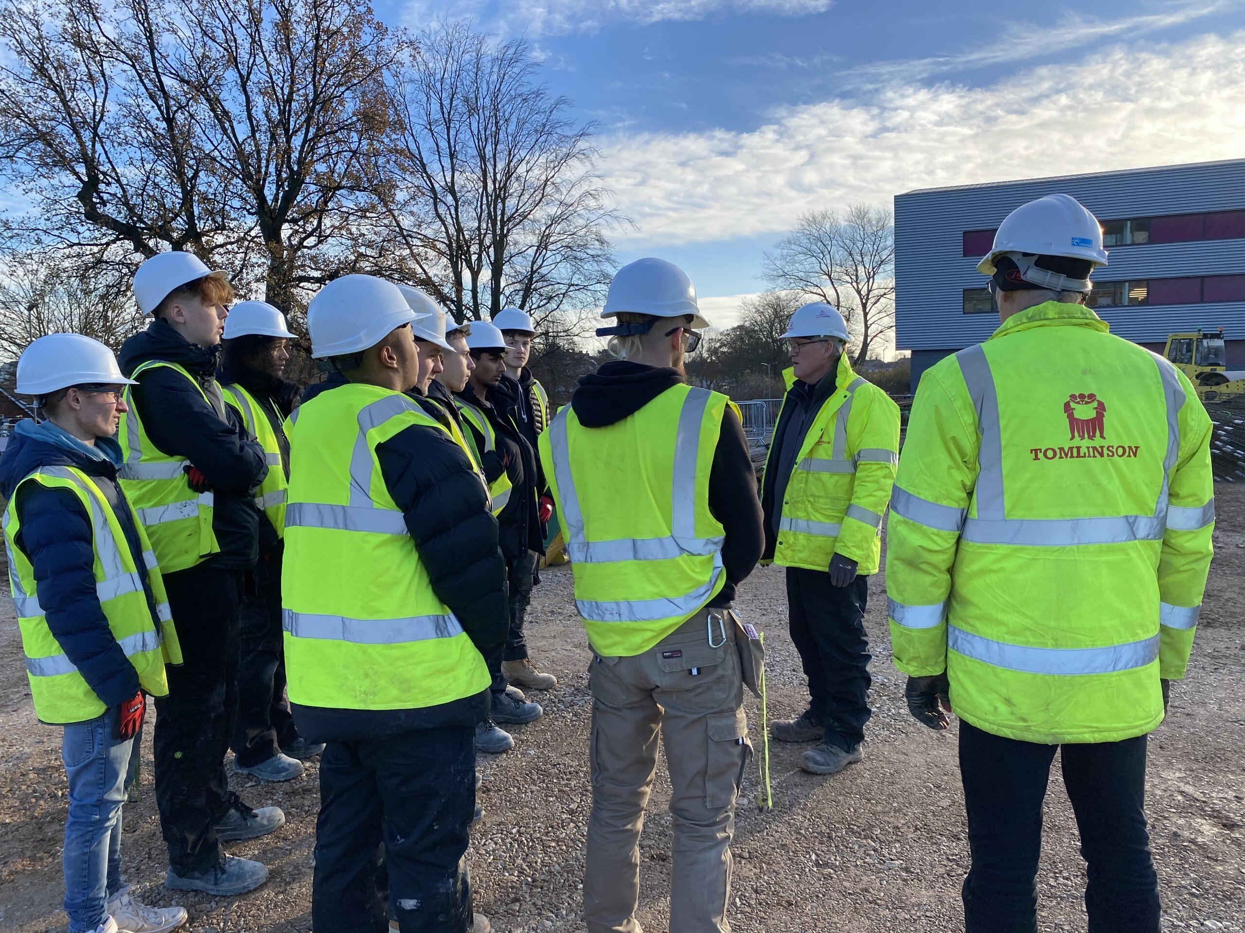 Construction students on a building site wearing hi vis jackets.