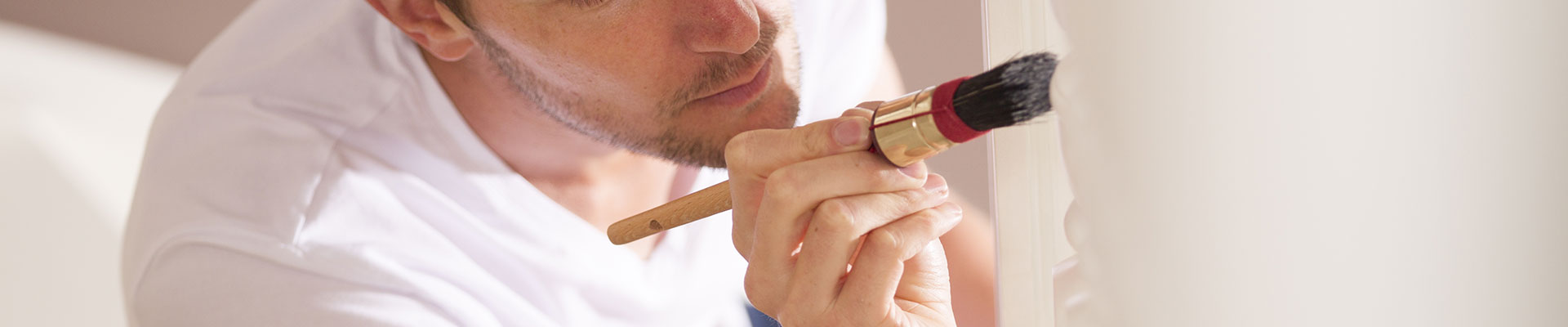 A painter cutting into a wall with a small paintbrush