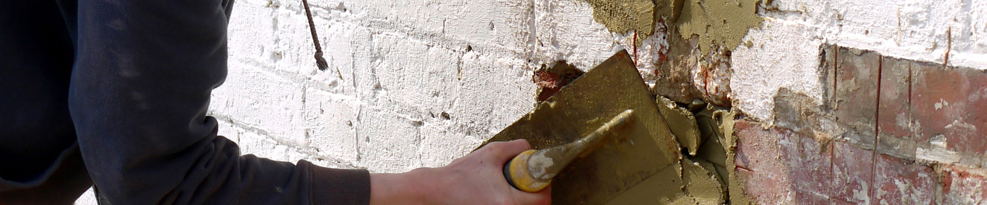 A student plastering a brick wall