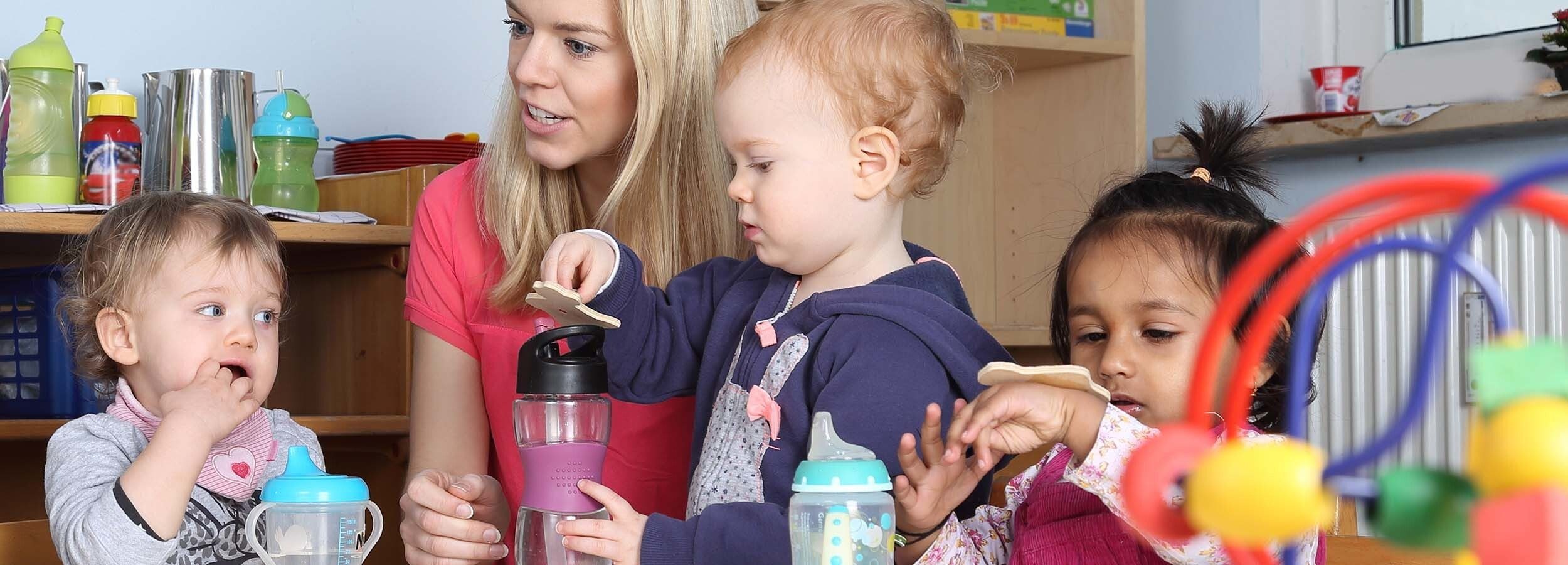 Three children in a nursery setting with a member of staff