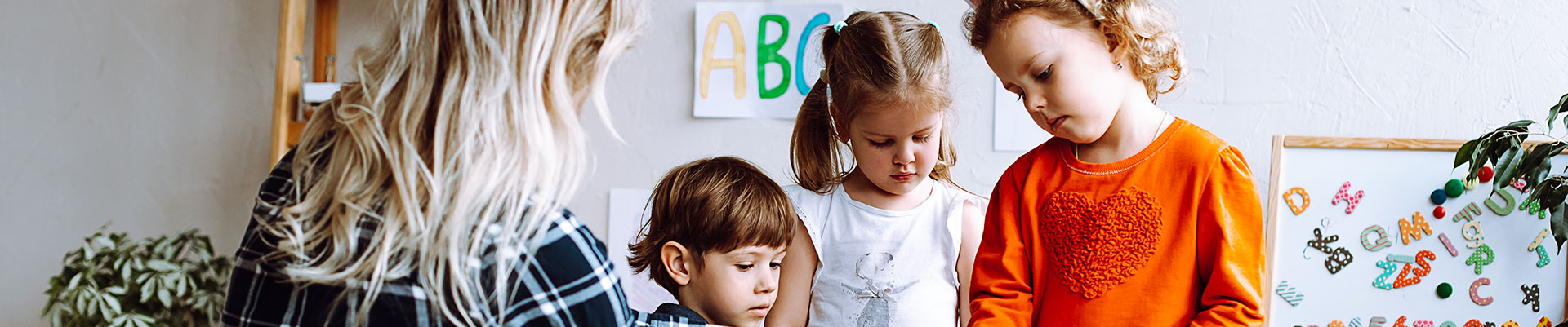 An early years educator working with three children in a nursery.