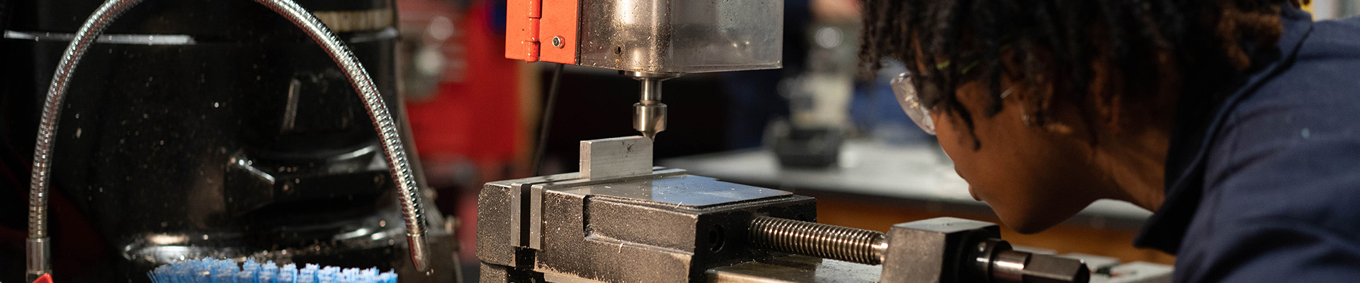 A student working on machinery in an engineering workshop.