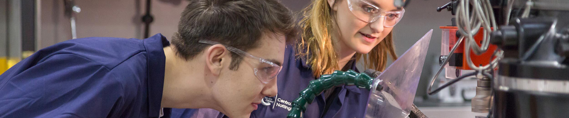 Two engineering students looking into a machine