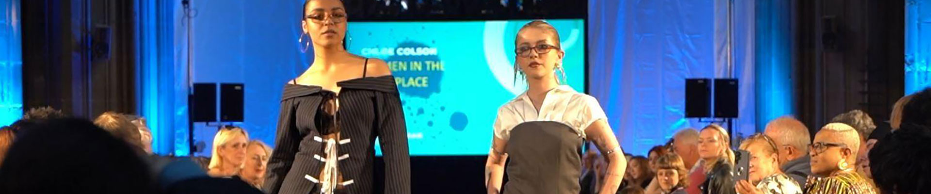 Two students on the catwalk wearing clothes designed by students