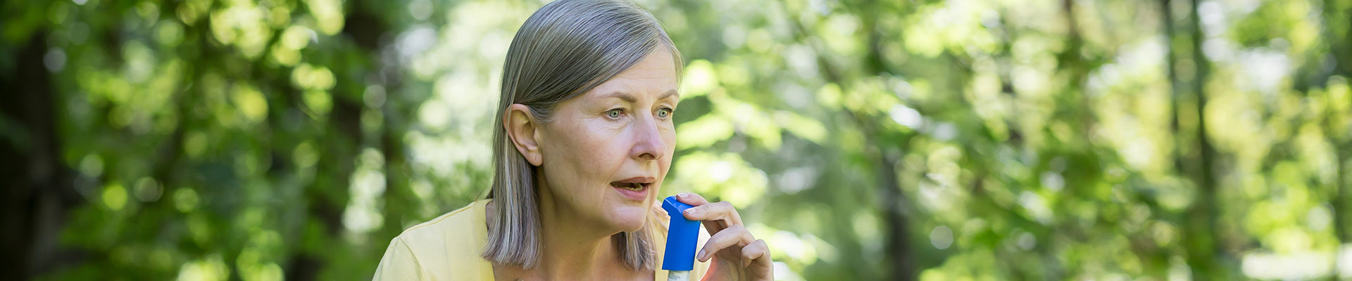 An older lady outside with an inhaler