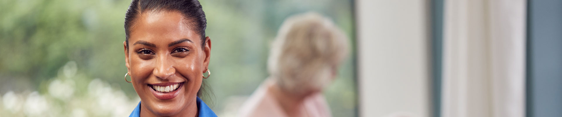 An adult care worker with older people in the background.