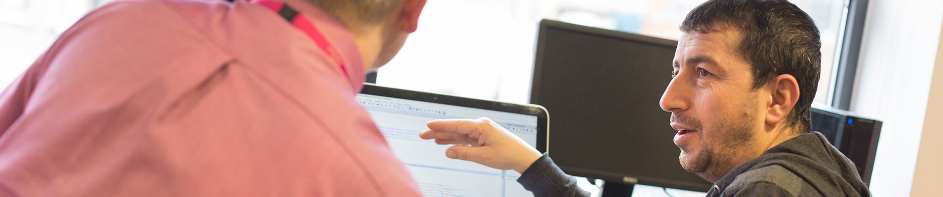 A student and lecturer pointing at a computer screen.