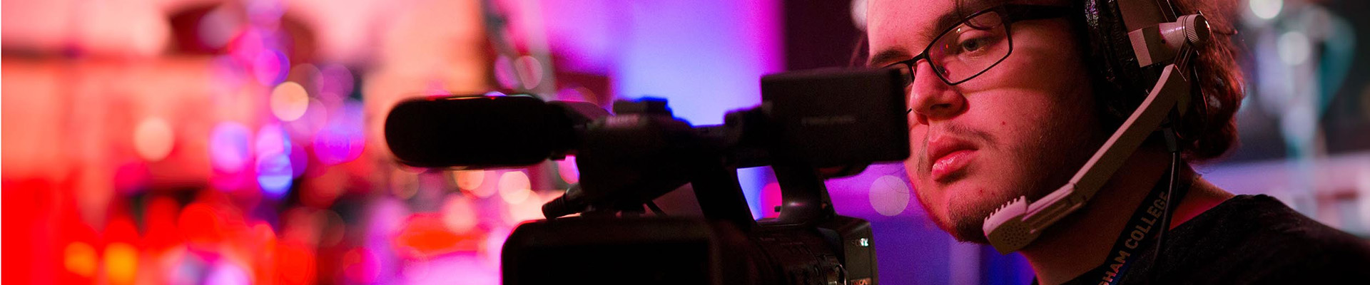 A student with a headset looking through the lens of a tv camera