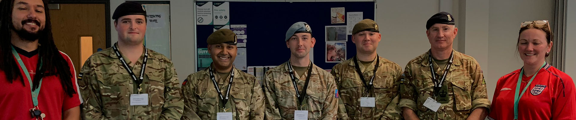 A group of soldiers posing for a photograph with college staff on an industry day.