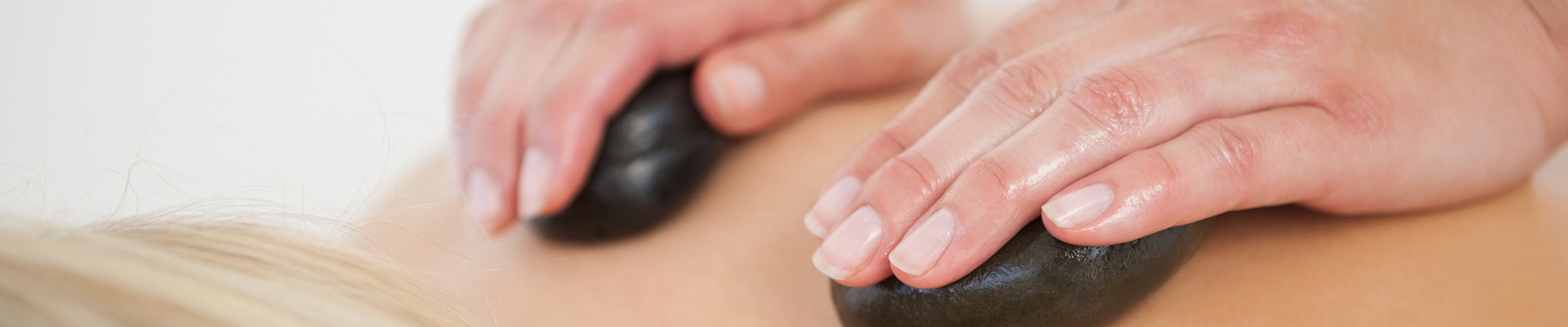 A student performing a hot stone massage on a client.
