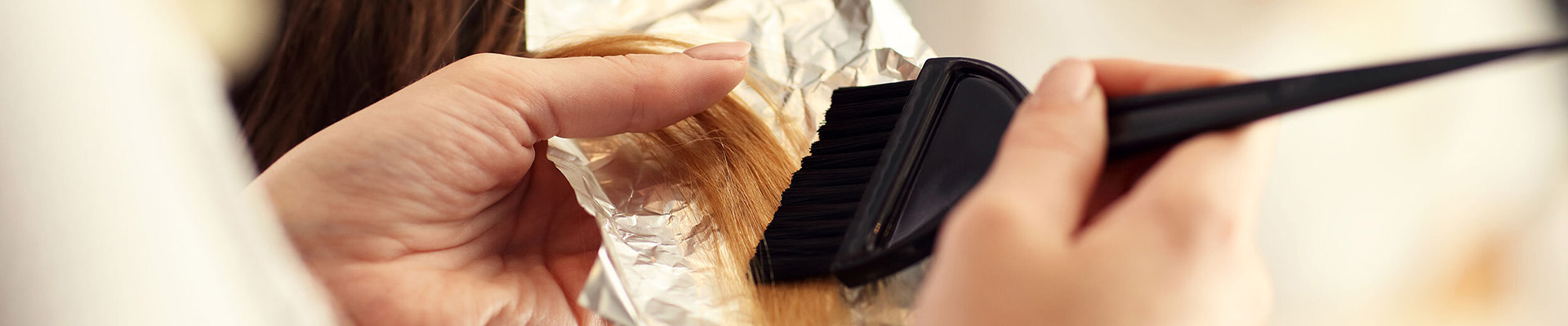 A hairdresser applying colour to a clients hair with foil