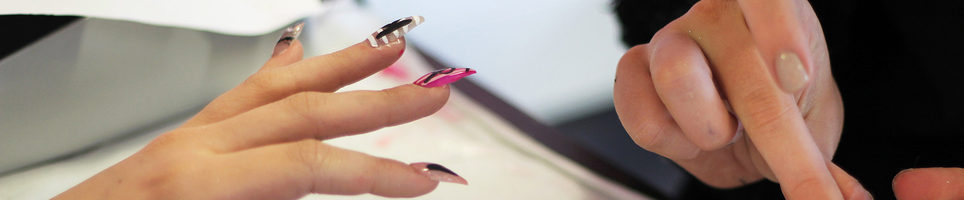 A student finishing a client's nails after a manicure