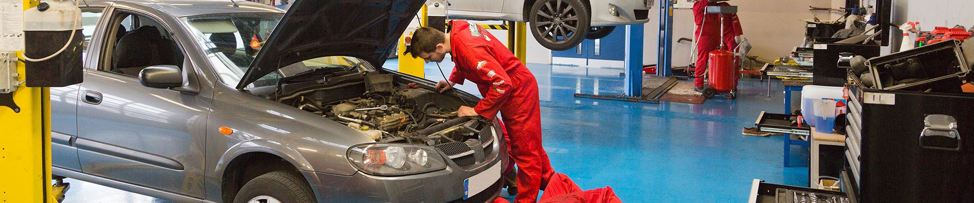 Students working on a car in an automotive workshop.